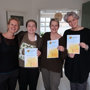 Drie vrouwen tonen elk een certificaat van YogaReiki-cursus